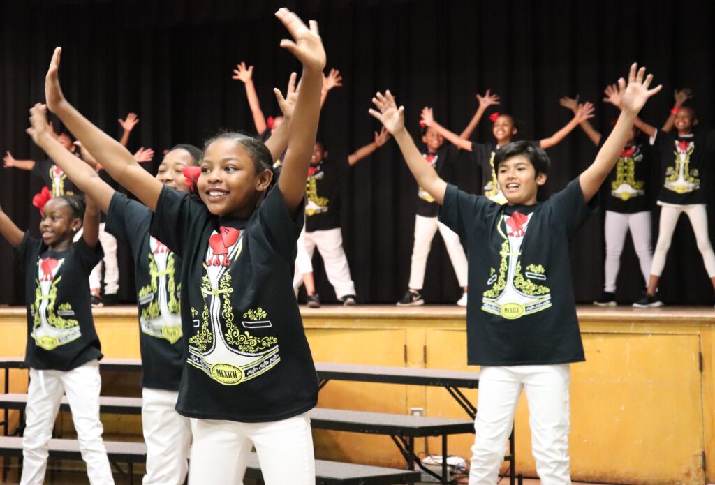 P.S. Arts Malinda's students lock on arms on stage as they perform a dance routine.