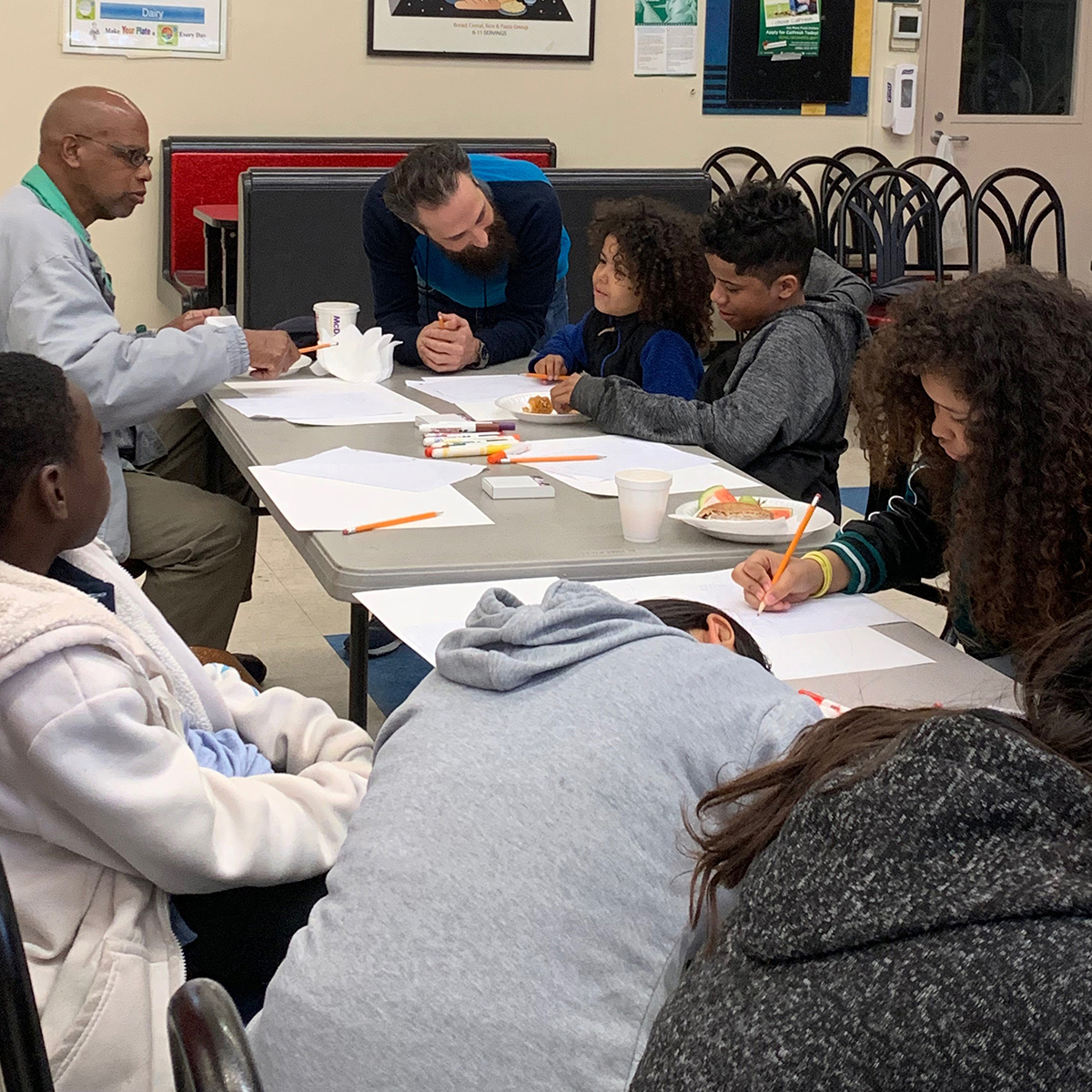 A table of adults and children work on with pencils and papers at the 2019 IOCA family workshops